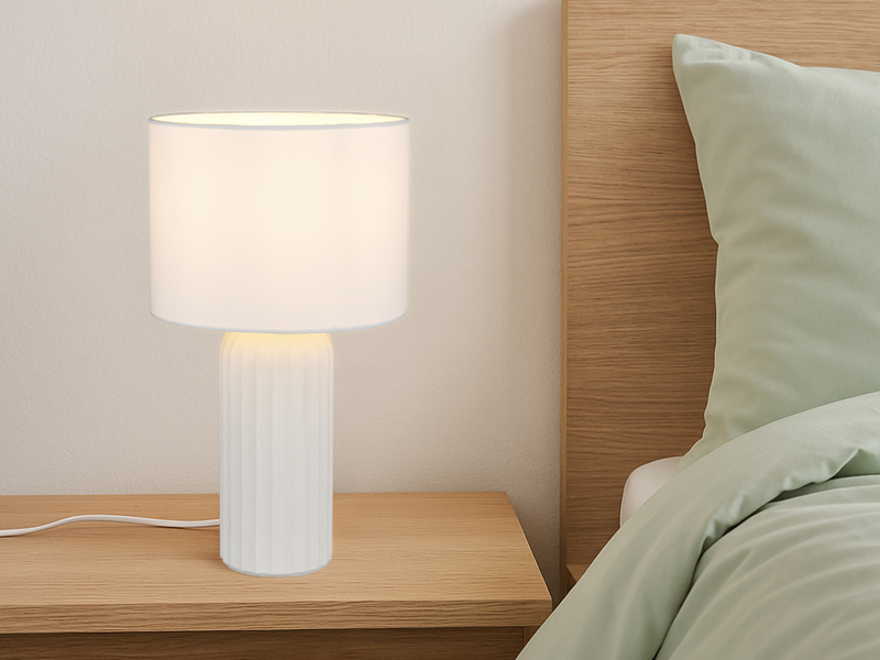 Weiße Tischleuchte mit Stoffschirm, auf einem Nachttisch im Schlafzimmer