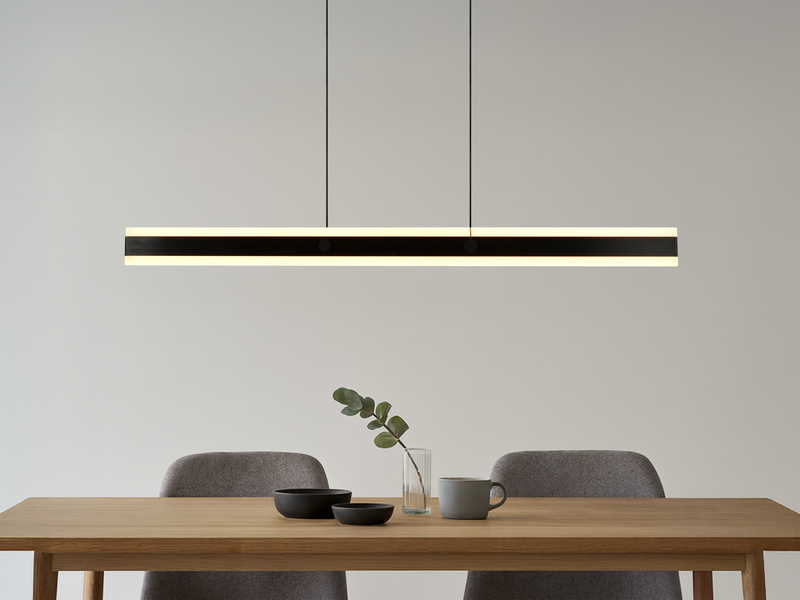 Lineare LED-Pendelleuchte in schwarz über einem Esstisch