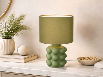 Grüne Tischleuchte mit Keramikfuß und Stoffschirm auf einer Kommode