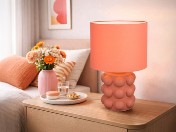 große orangene Tischleuchte mit Keramikfuß und Stoffschirm auf einer Kommode