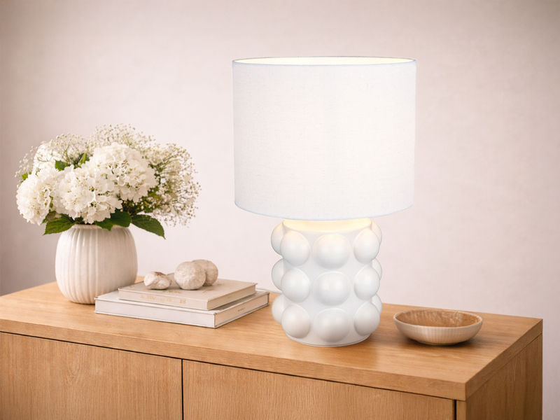 Große weiße Tischleuchte mit Keramikfuß und Stoffschirm auf einer Kommode