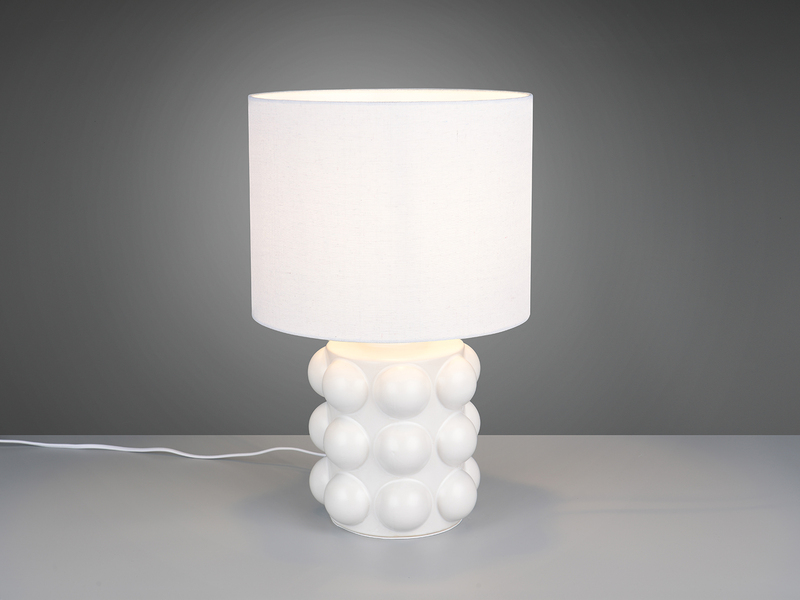 große weiße Retro-Tischleuchte mit kugelförmig strukturiertem Keramikfuß und Stoffschirm angeschaltet