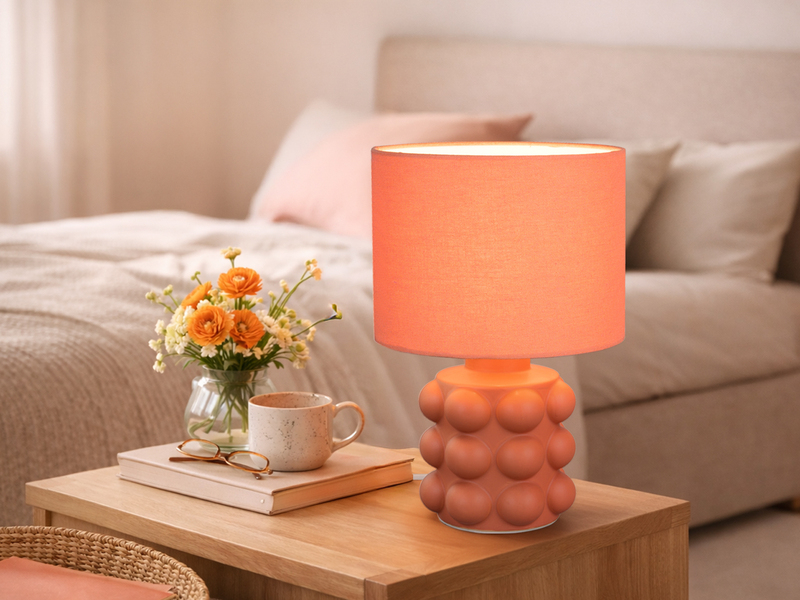 Orangene Tischleuchte mit Keramikfuß und Stoffschirm auf einer Kommode