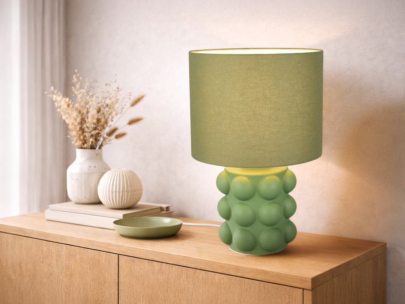 große grüne Tischleuchte mit Keramikfuß und Stoffschirm auf einer Kommode