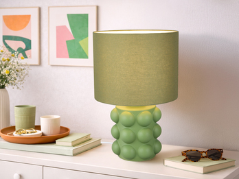große grüne Tischleuchte mit Keramikfuß und Stoffschirm auf einer Kommode