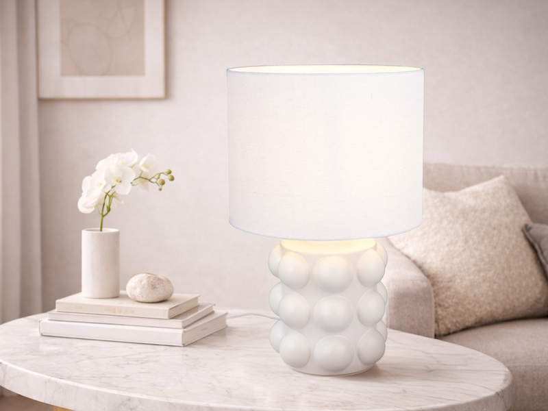 Große weiße Tischleuchte mit Keramikfuß und Stoffschirm auf einem Beistelltisch