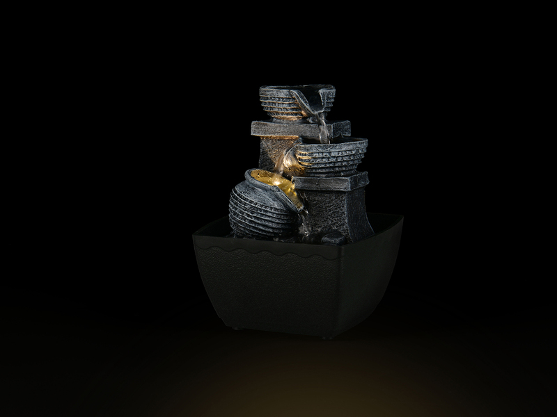 Beleuchteter Zimmerbrunnen mit Krug vor dunklem Hintergrund