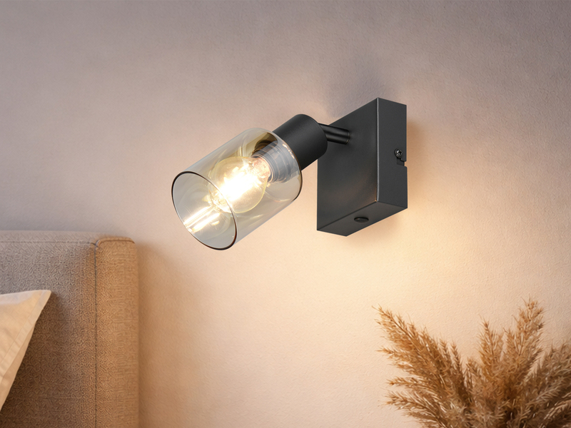 Einflammige Wandstrahler mit amberfarbigem Glasschirm neben dem Bett