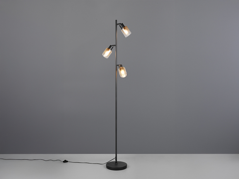 Stehlampe mit schwarzem Fuß und drei amberfarbigen Glas Spots eingeschaltet im Raum stehend
