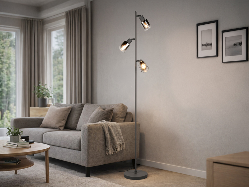 Stehlampe mit schwarzem Fuß und drei Chrom Glas Spots in einem Wohnzimmer neben dem Sofa stehend