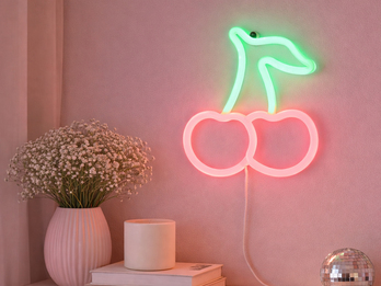 Neon-Wandlampe in Kirschform als dekorative Wandbeleuchtung über einem Tisch