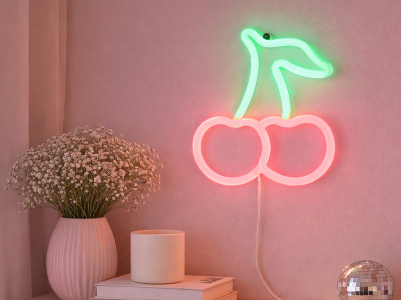 Neon-Wandlampe in Kirschform als dekorative Wandbeleuchtung über einem Tisch